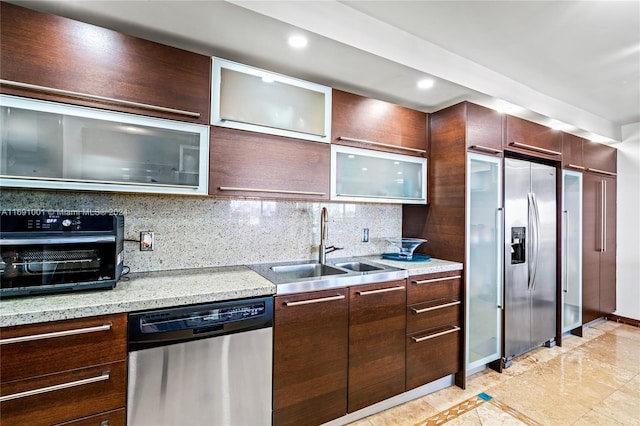 kitchen with stainless steel appliances, sink, light stone counters, and backsplash