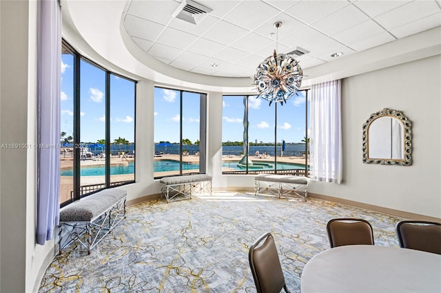 interior space featuring a drop ceiling, a wealth of natural light, and a notable chandelier