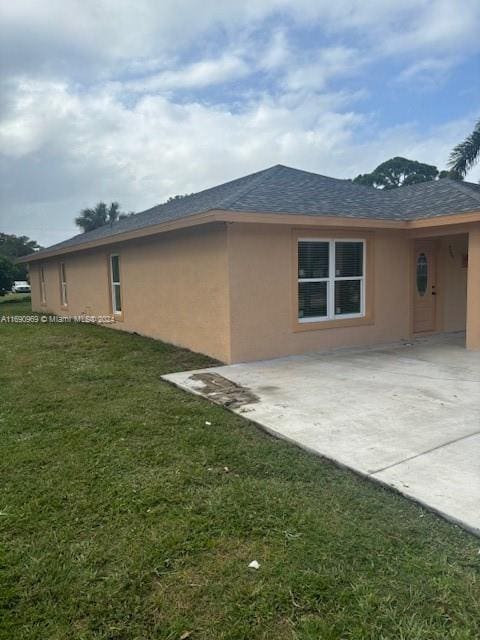 view of side of property with a patio and a lawn