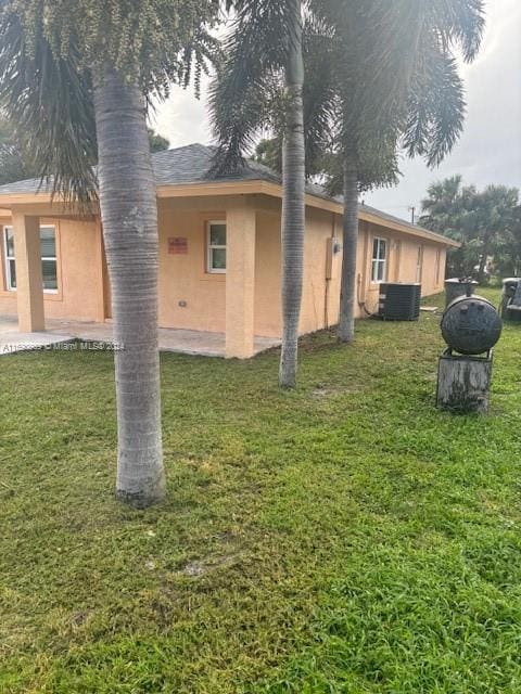 view of side of property featuring central air condition unit, a lawn, and a patio