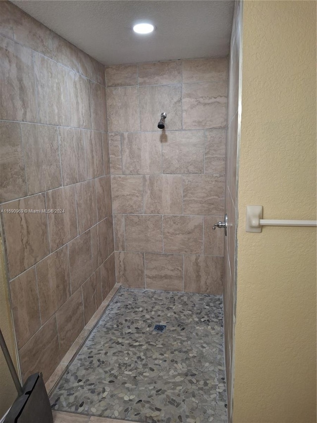 bathroom featuring a textured ceiling and a tile shower