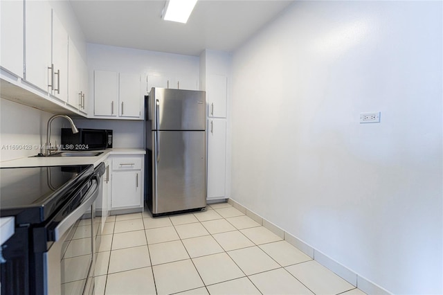 kitchen with white cabinetry, sink, light tile patterned floors, range with electric stovetop, and stainless steel fridge