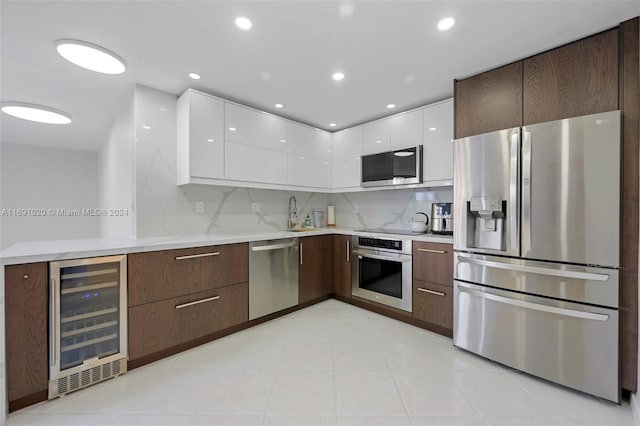 kitchen with tasteful backsplash, wine cooler, appliances with stainless steel finishes, dark brown cabinets, and white cabinets