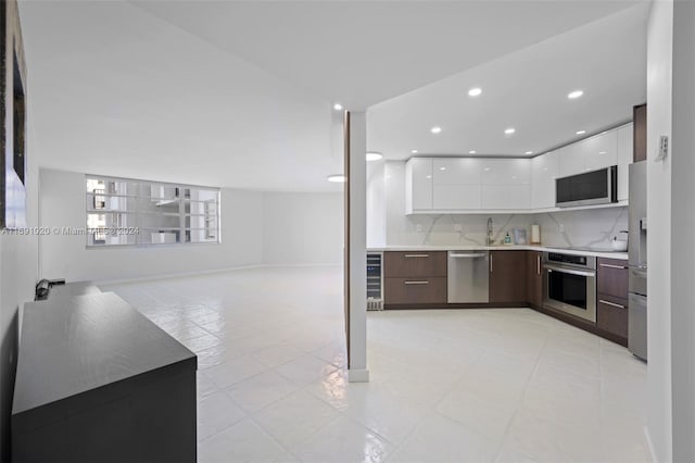 kitchen featuring white cabinetry, wine cooler, appliances with stainless steel finishes, tasteful backsplash, and dark brown cabinets