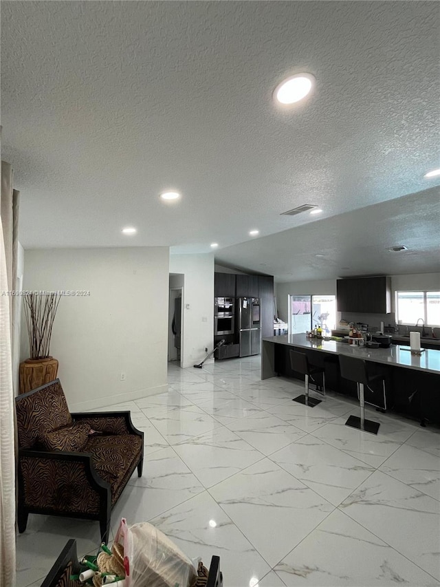 living room with a wealth of natural light, sink, and a textured ceiling