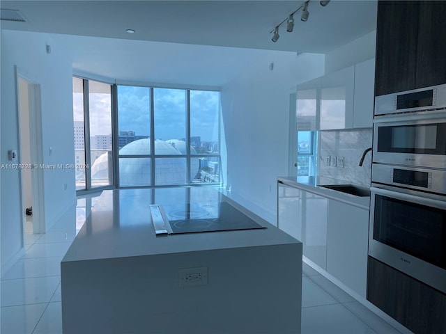 kitchen with black electric cooktop, white cabinetry, sink, light tile patterned floors, and double oven