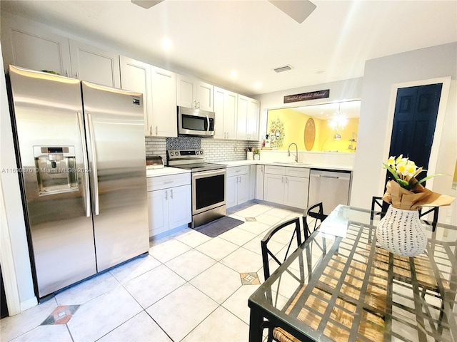 kitchen with white cabinetry, sink, stainless steel appliances, backsplash, and light tile patterned floors