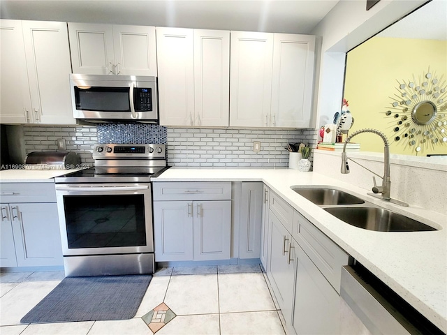 kitchen with white cabinetry, sink, stainless steel appliances, decorative backsplash, and light tile patterned flooring