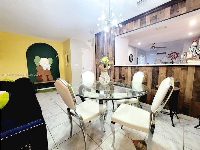 dining space featuring ceiling fan, wood walls, and light tile patterned floors