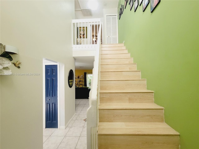 stairway with tile patterned flooring, a high ceiling, and a healthy amount of sunlight