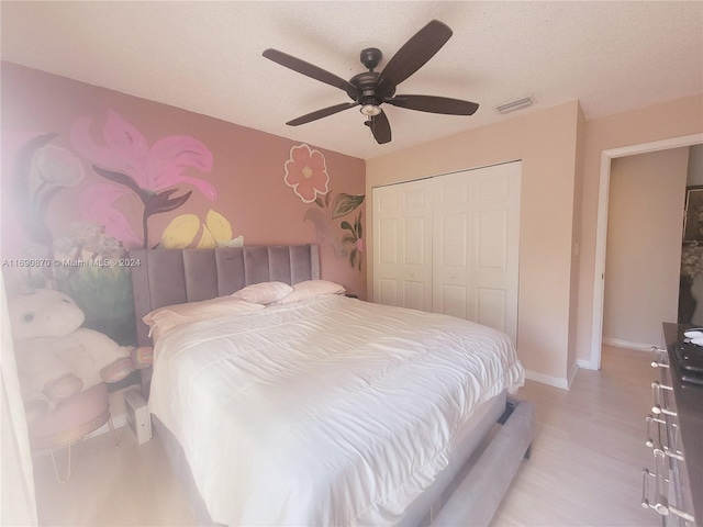 bedroom with ceiling fan, light hardwood / wood-style floors, a textured ceiling, and a closet