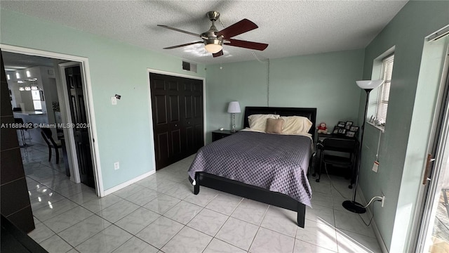 tiled bedroom with a textured ceiling, ceiling fan, and a closet