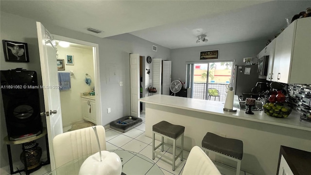 kitchen featuring white cabinetry, stainless steel appliances, light tile patterned floors, and backsplash