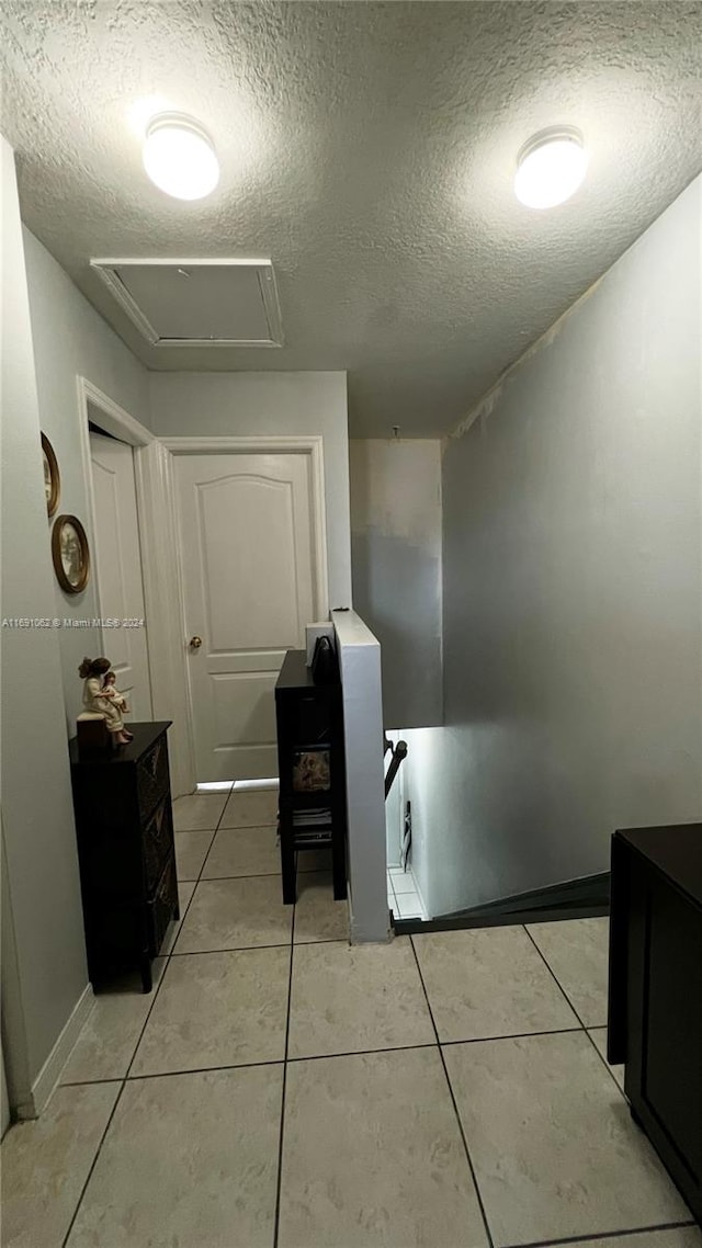 laundry area featuring a textured ceiling and light tile patterned floors