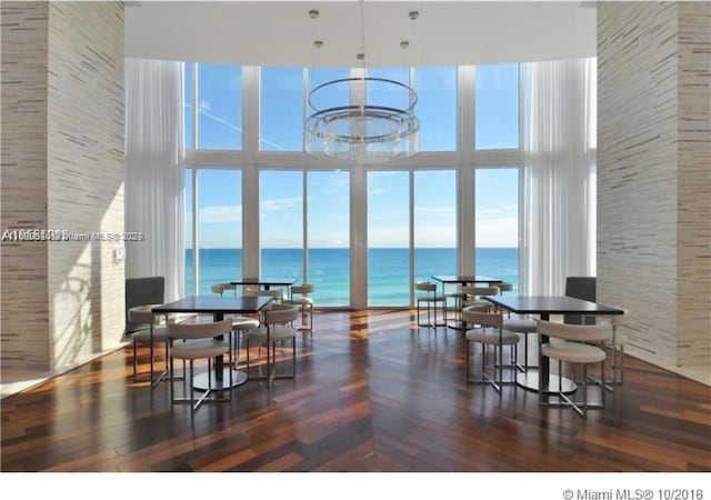 dining room with dark hardwood / wood-style flooring, a water view, and a high ceiling