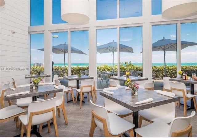 dining space with a towering ceiling, plenty of natural light, a water view, and wood-type flooring