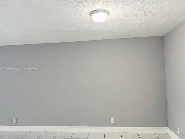 tiled empty room featuring a textured ceiling