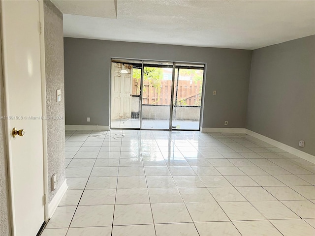 unfurnished room featuring a textured ceiling and light tile patterned flooring