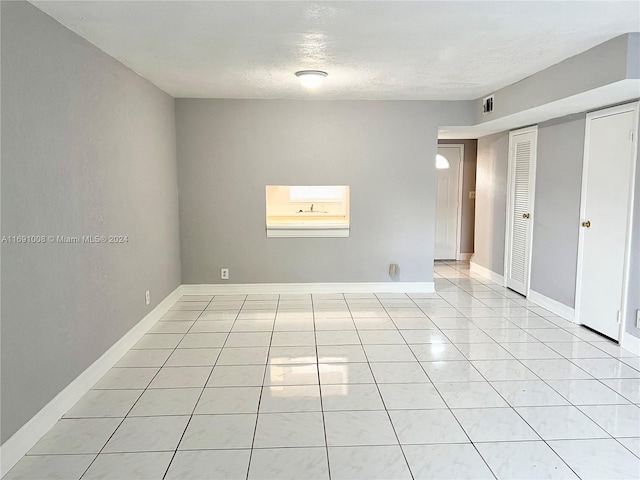 unfurnished room with a textured ceiling and light tile patterned floors