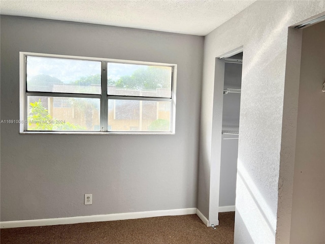 unfurnished bedroom featuring a closet, a textured ceiling, and carpet flooring