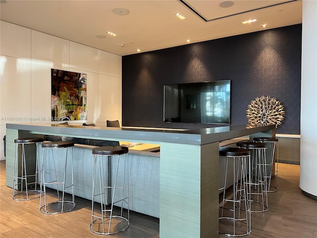 bar with white cabinets and light hardwood / wood-style flooring