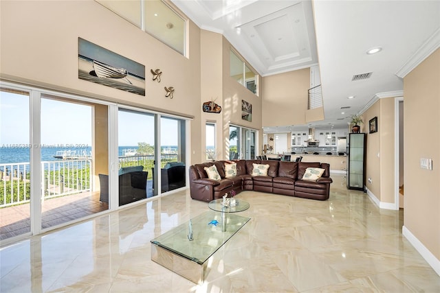 living room featuring a high ceiling, a water view, and ornamental molding