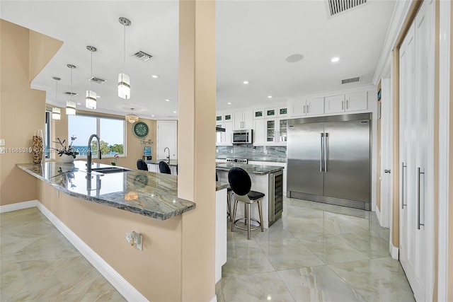 kitchen featuring hanging light fixtures, backsplash, a breakfast bar, white cabinetry, and appliances with stainless steel finishes