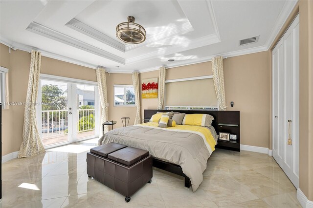 bedroom with crown molding, a tray ceiling, and two closets