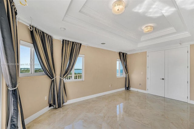 unfurnished bedroom with a raised ceiling, a closet, and ornamental molding