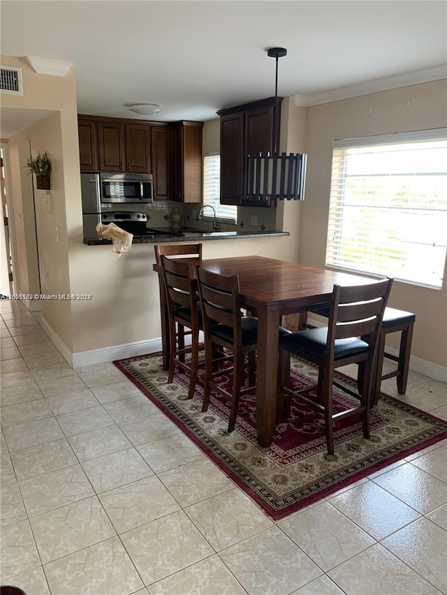 dining area featuring light tile patterned floors and ornamental molding