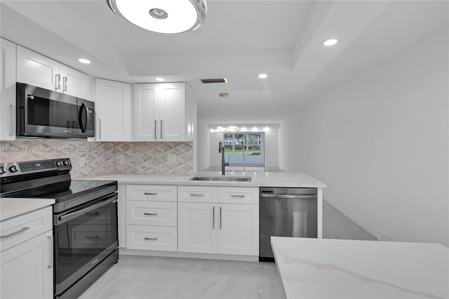 kitchen with stainless steel appliances, sink, light stone counters, tasteful backsplash, and white cabinets