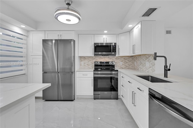 kitchen featuring white cabinetry, stainless steel appliances, sink, and light stone countertops