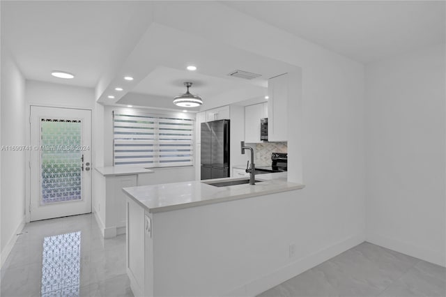 kitchen with tasteful backsplash, stainless steel appliances, sink, white cabinets, and kitchen peninsula