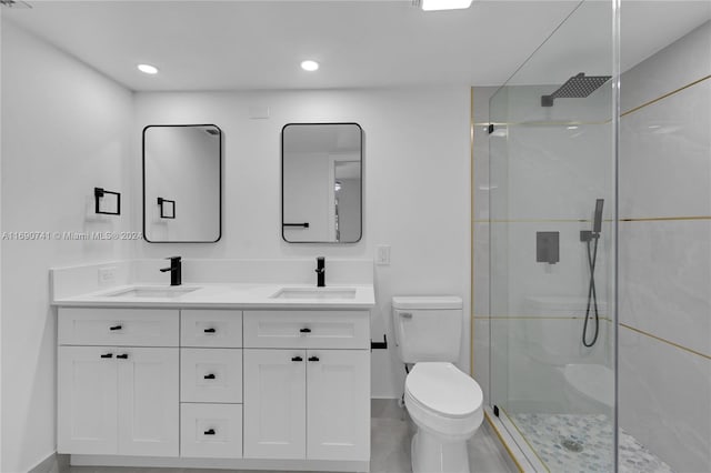 bathroom with a shower with shower door, vanity, and toilet