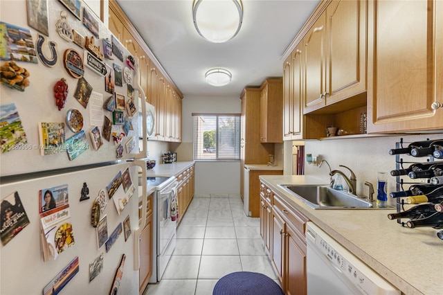 kitchen with light tile patterned floors, white appliances, light brown cabinetry, and sink