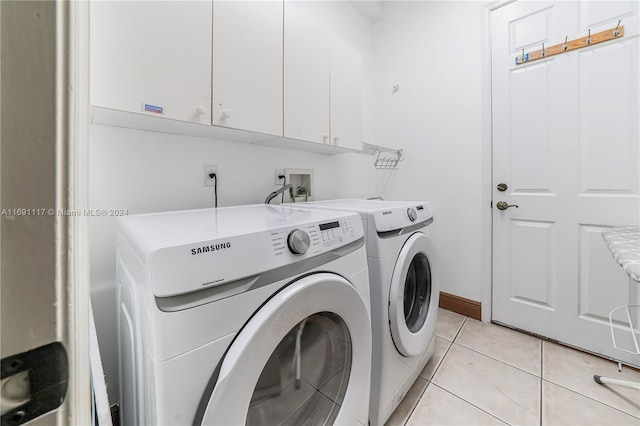 laundry room with washer and clothes dryer, light tile patterned flooring, and cabinets