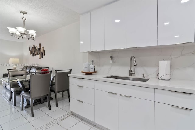 kitchen featuring white cabinetry, decorative light fixtures, decorative backsplash, sink, and a chandelier