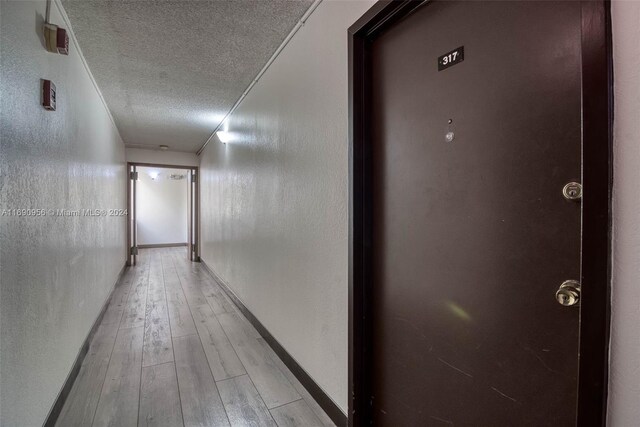 hall featuring light hardwood / wood-style flooring and a textured ceiling