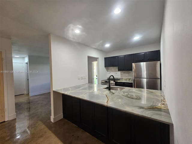 kitchen with light stone countertops, stainless steel fridge, kitchen peninsula, and sink