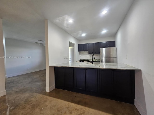 kitchen featuring stainless steel refrigerator, dark colored carpet, kitchen peninsula, and sink