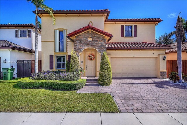 mediterranean / spanish house featuring a garage and a front yard