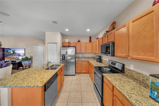 kitchen with sink, light tile patterned floors, a kitchen island with sink, stainless steel appliances, and light stone counters