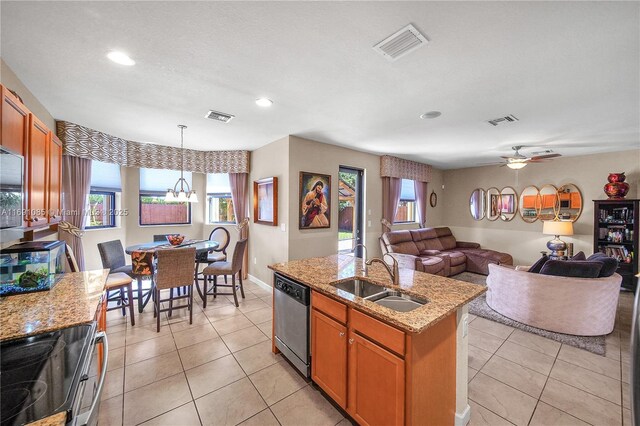 kitchen featuring pendant lighting, an island with sink, sink, stainless steel dishwasher, and light stone counters