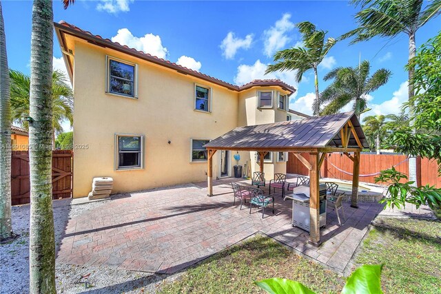 back of property featuring a gazebo and a patio area