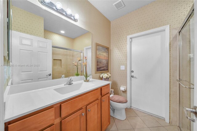 bathroom featuring tile patterned flooring, an enclosed shower, vanity, and toilet