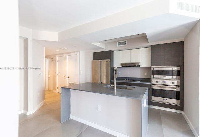 kitchen with a kitchen island with sink, stainless steel appliances, white cabinetry, and sink