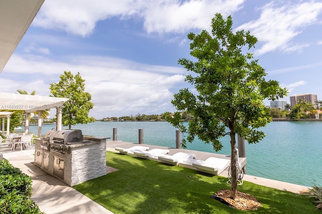 dock area featuring exterior kitchen, a water view, a lawn, and a pergola