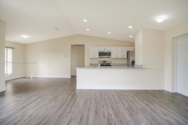 kitchen with stainless steel appliances, light stone counters, kitchen peninsula, light hardwood / wood-style floors, and white cabinets