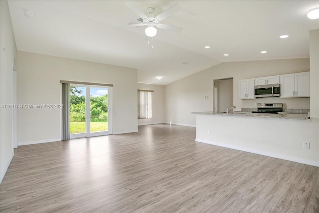 unfurnished living room featuring ceiling fan, lofted ceiling, sink, and light hardwood / wood-style flooring