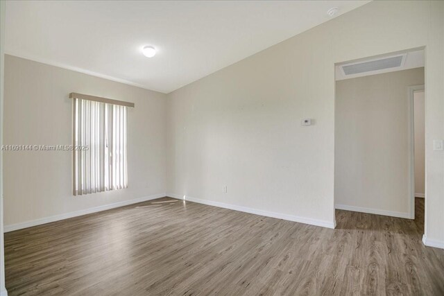 spare room with lofted ceiling and hardwood / wood-style flooring